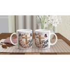 White ceramic mug with faith-themed design, pink roses, butterflies, and gold cross, on a wooden table with plants