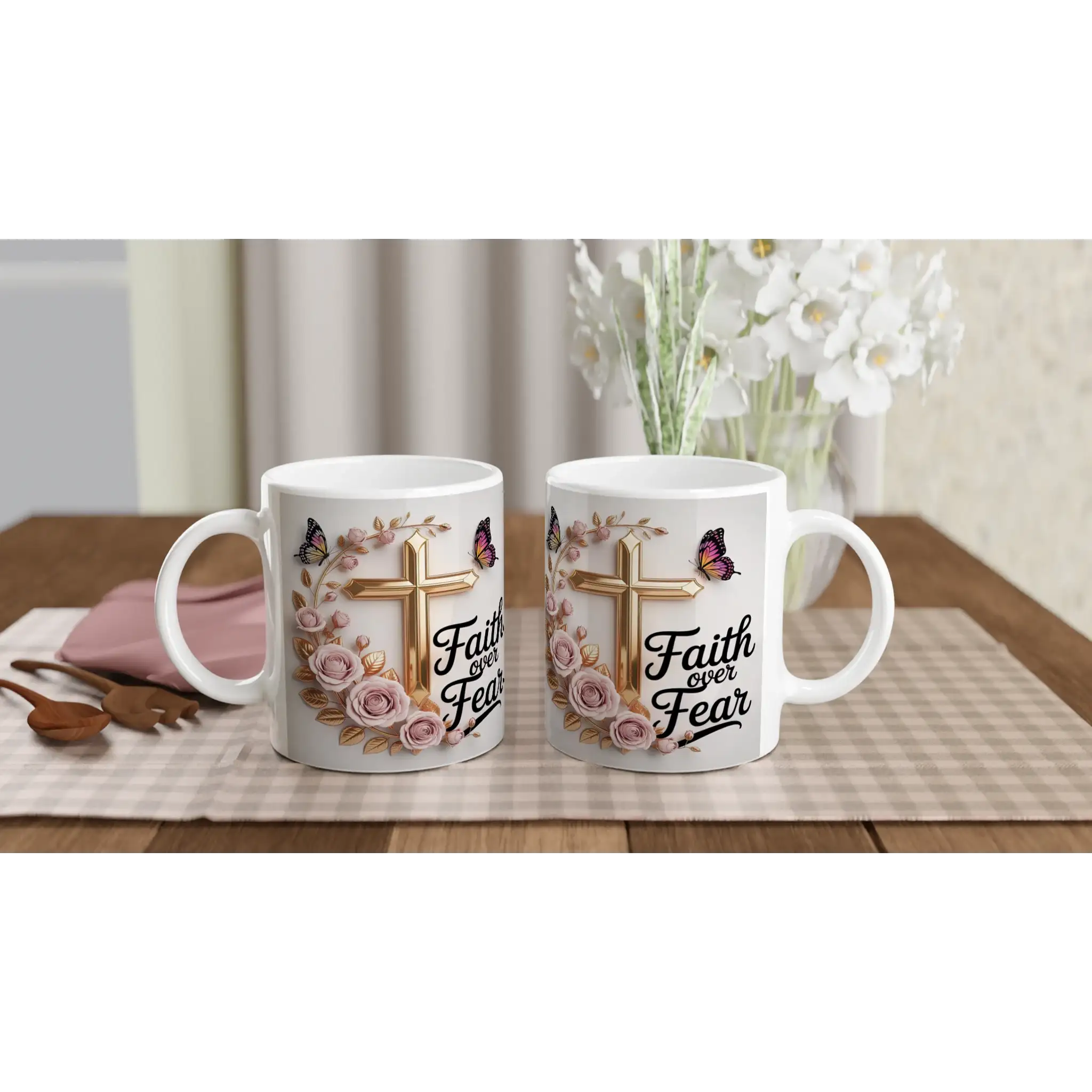 White ceramic mug with faith-themed design, pink roses, butterflies, and gold cross, on a wooden table with plants