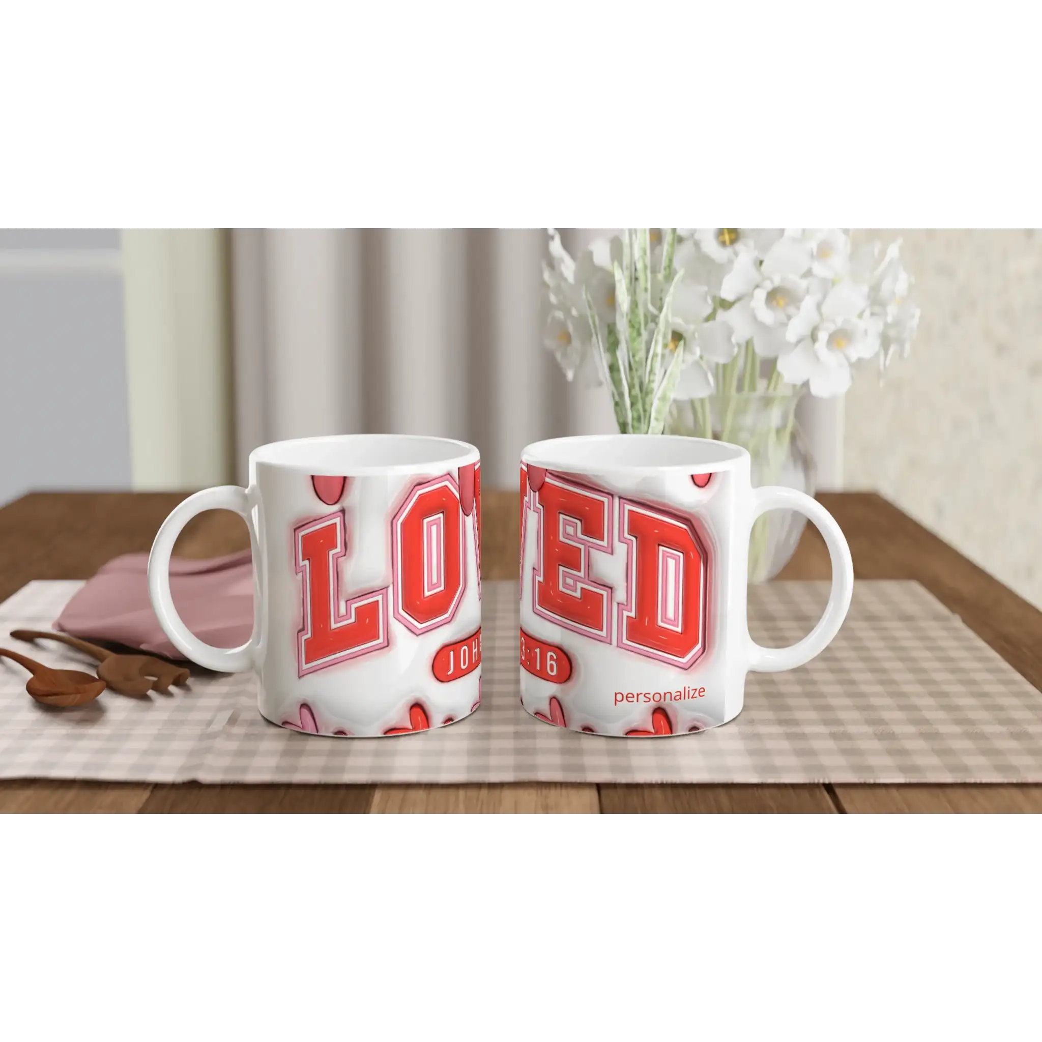 White ceramic mugs with red and pink geometric designs, on a checkered tablecloth with a pink napkin and wooden spoon