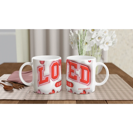 White ceramic mugs with red and pink geometric designs, on a checkered tablecloth with a pink napkin and wooden spoon