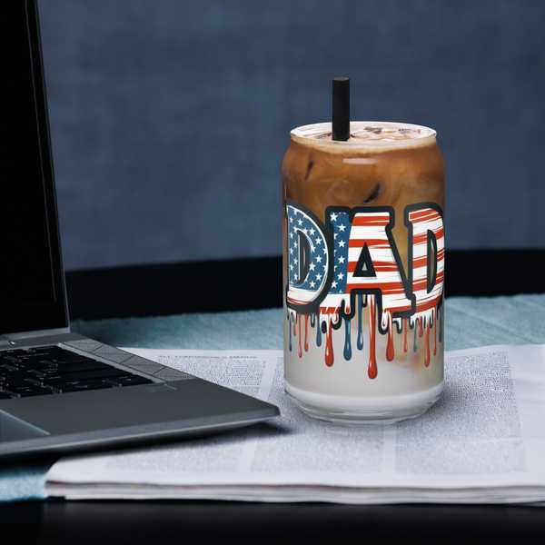 Can-shaped glass for drinks with patriotic design and straw on workspace